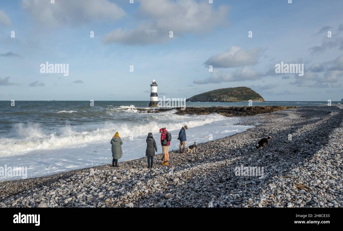 Die Familie genießt einen Spaziergang am Kiesstrand in Penmon, Anglesey, Wales Stockfoto