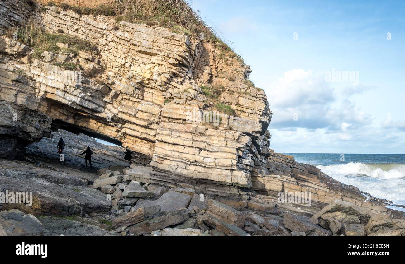 Der Tunnel unter einer Klippe, die eine Brücke in Penmon, Anglesey, Wales bildet. Stockfoto