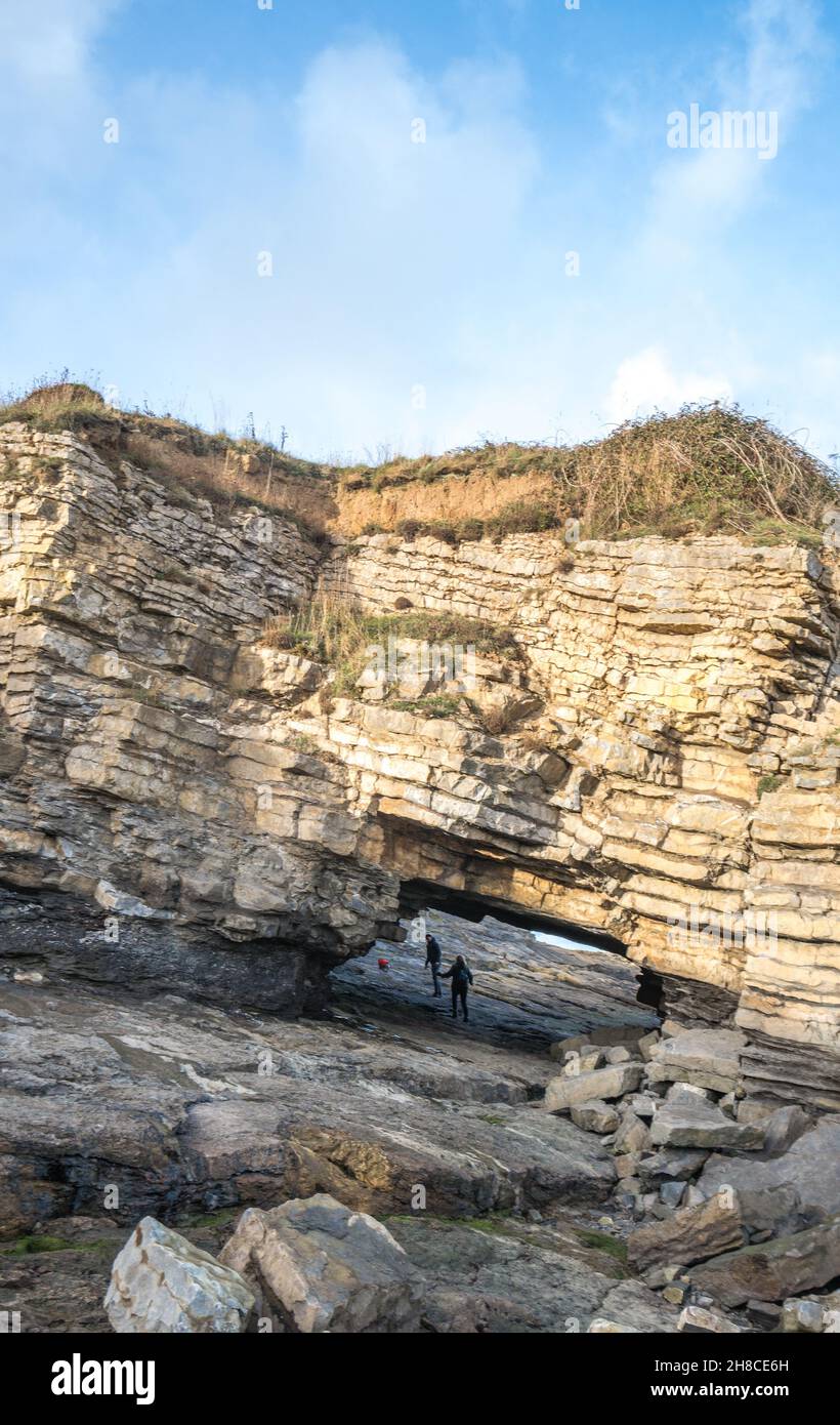 Der Tunnel unter einer Klippe, die eine Brücke in Penmon, Anglesey, Wales bildet. Stockfoto