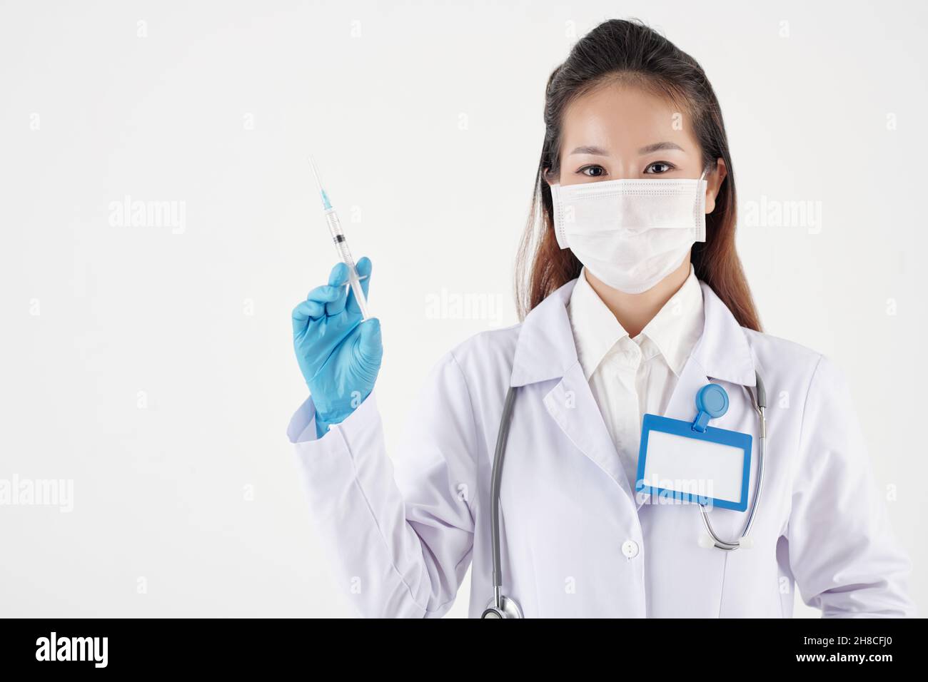 Hübsche junge Ärztin, die eine Spritze mit Impfstoff oder Medizin im Inneren hält Stockfoto