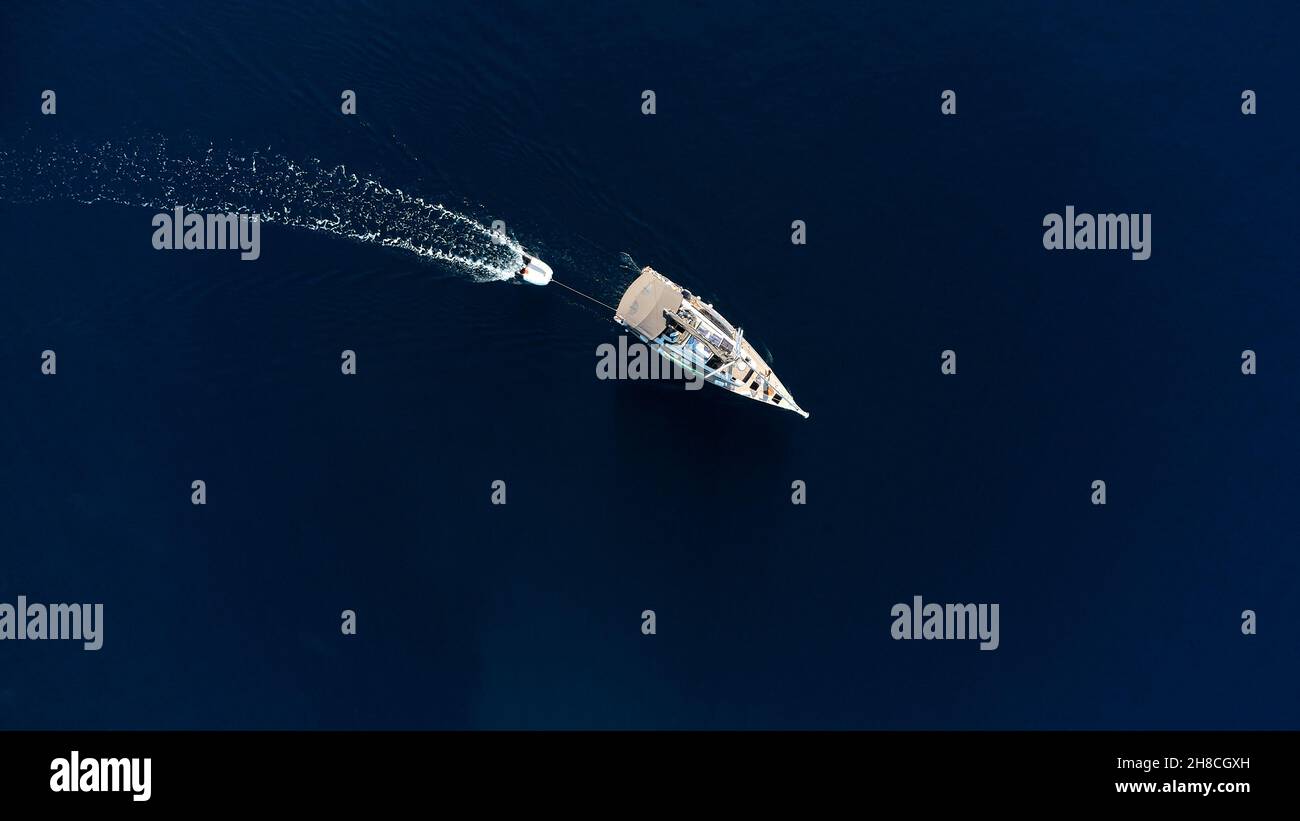 Private Yacht, mit einem aufblasbaren Boot an der Rückseite gebunden, segelt auf dem blauen Meer. Luftdrohne, extrem breites Foto von oben nach unten Stockfoto