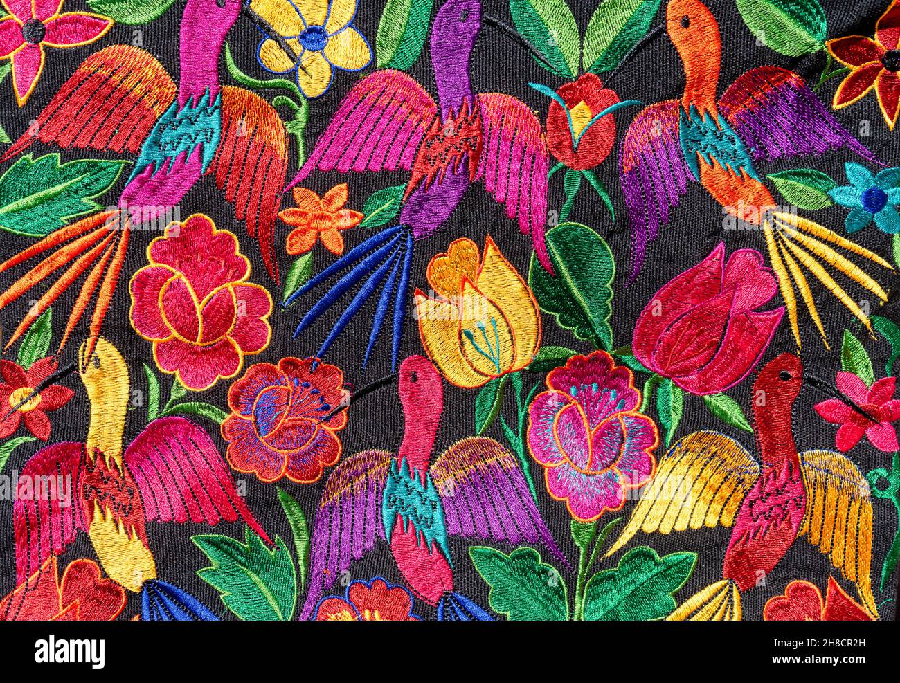 Detail aus buntem Stoff aus Chiapas, Mexiko. Vollständig handgefertigte Designs von Blumen und Vögeln in verschiedenen Farben. Stockfoto
