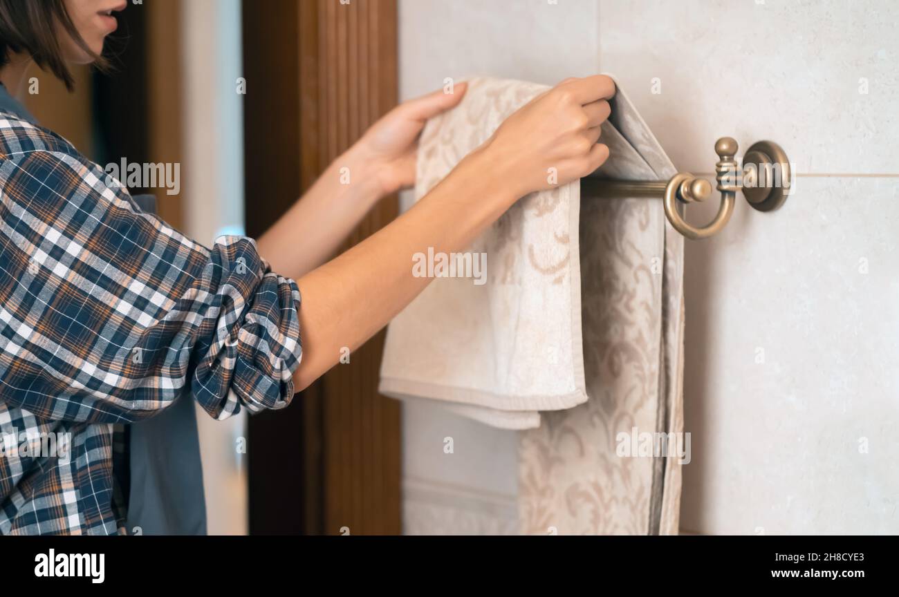 Mädchen hängt sauberes Handtuch auf einen Halter. Stockfoto