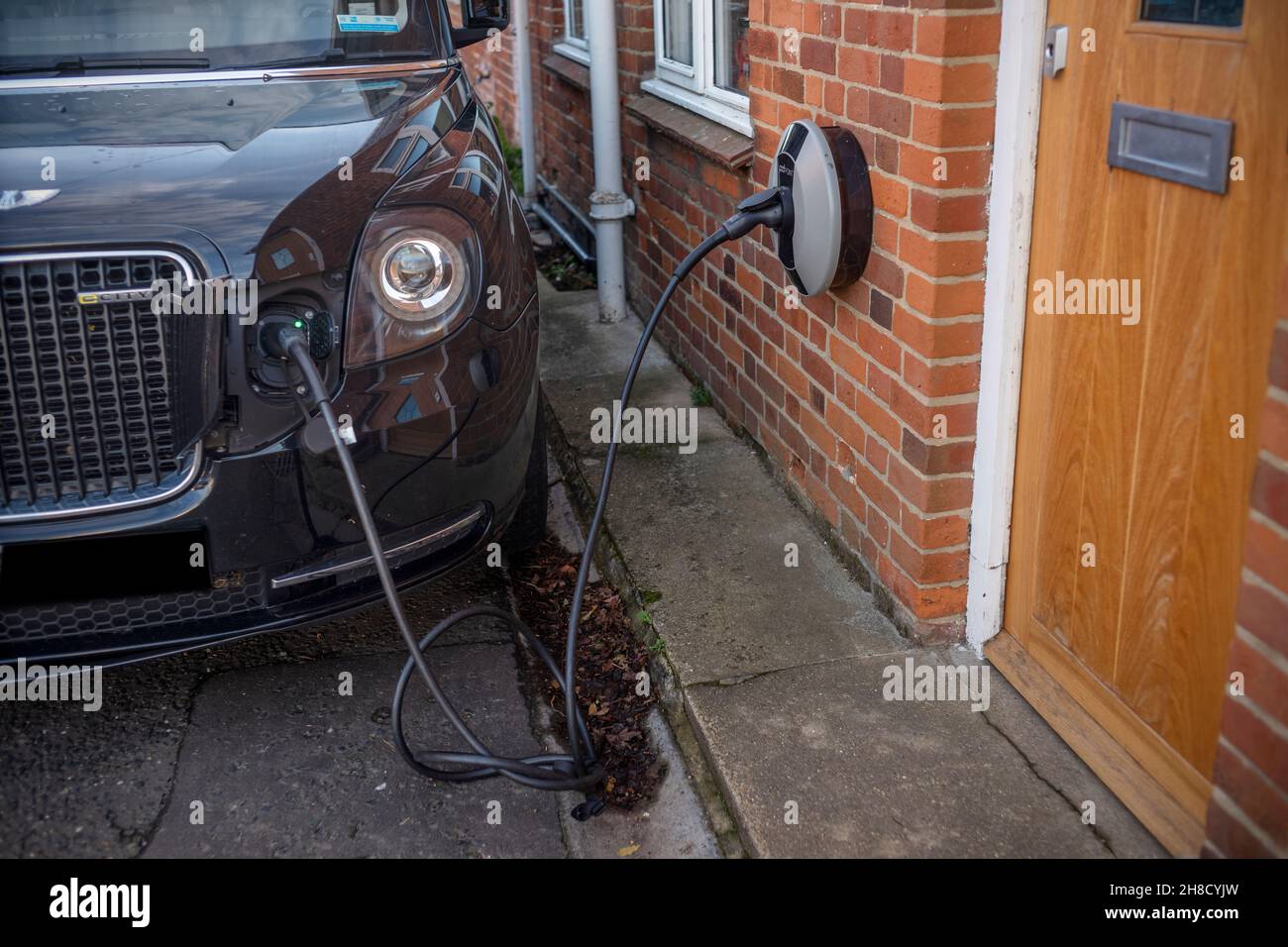 Thaxted Essex UK Electric London Taxi Charging November 2021 Electric London Taxi Charging up an elektrischen chraging-Punkt an Wand der privaten h befestigt Stockfoto