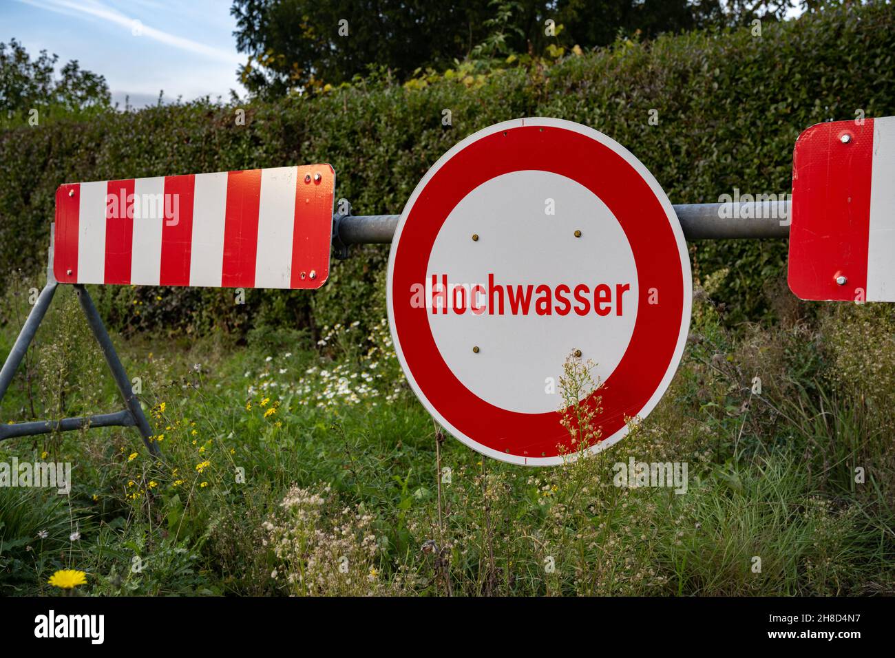 Rot-weißes deutsches Straßenschild „Hochwasser“, was „Flut“ bedeutet. Stockfoto