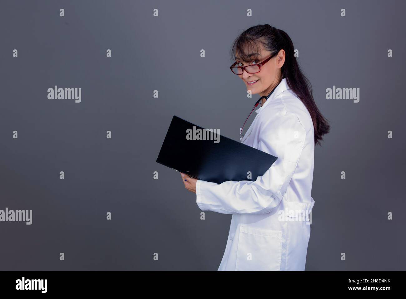 kaukasische Ärztin im Jahr 40s mit langer Haarmappe in der Hand, Seite zur Kamera. Stockfoto