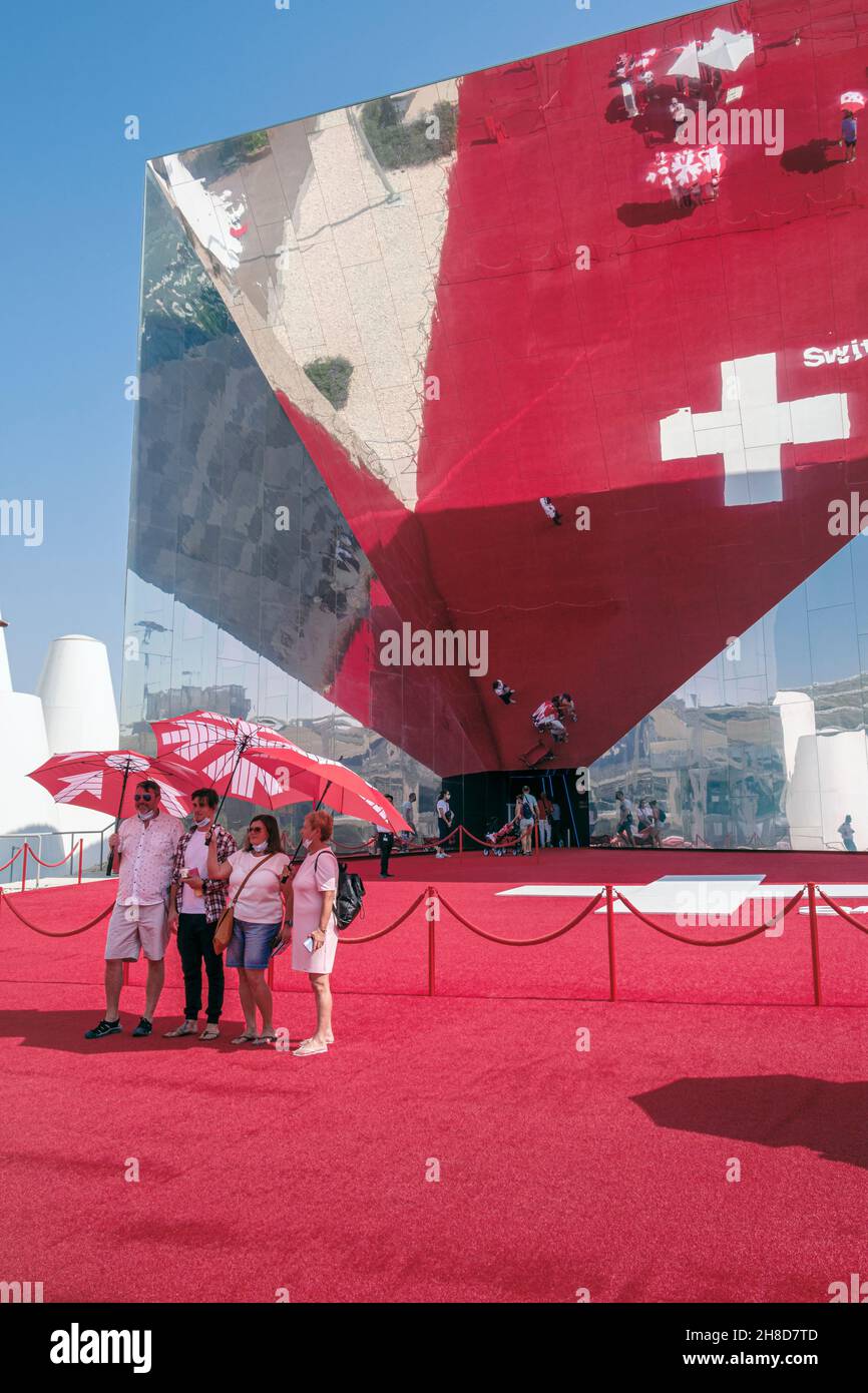 Die Besucher erhielten rote Regenschirme, die vor dem Schweizer Pavillon posieren sollten, der ein riesiger Spiegel war, der den roten Teppich der Expo 2020, Dubai, VAE, reflektierte Stockfoto