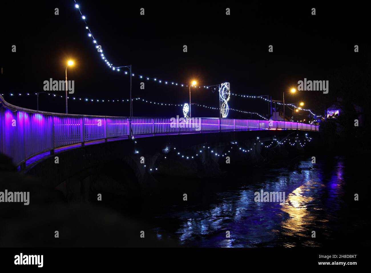 Weihnachtslichter auf der Martin Savage Bridge spiegeln sich in den Gewässern des Owenmore River, Ballisodare, County Sligo, Irland Stockfoto