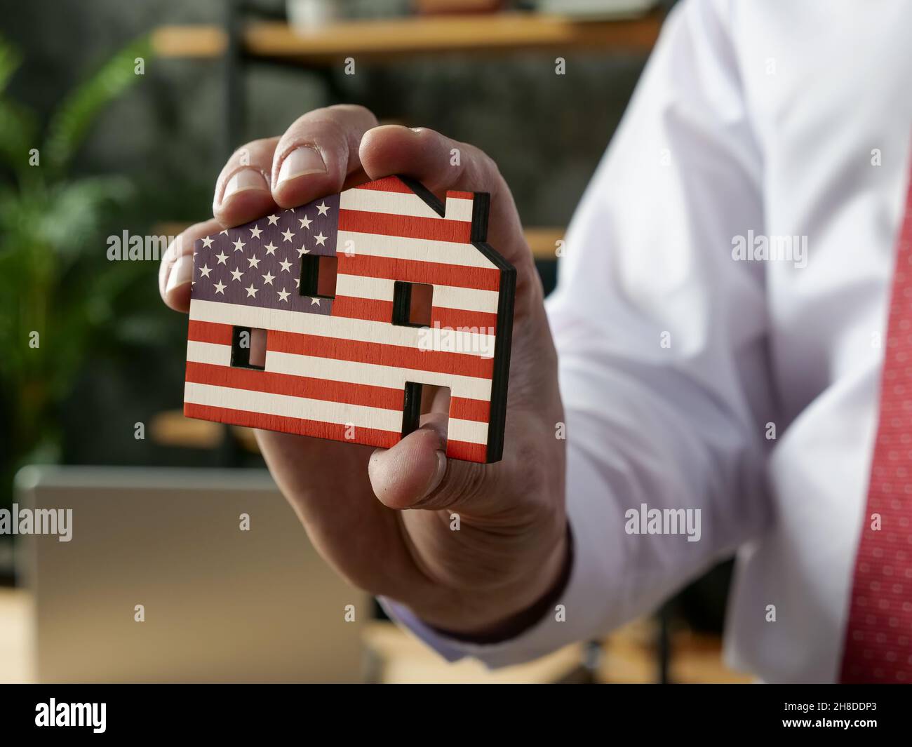 VA-Leihkonzept. Der Manager hält das Haus in den Farben der US-Flagge. Stockfoto