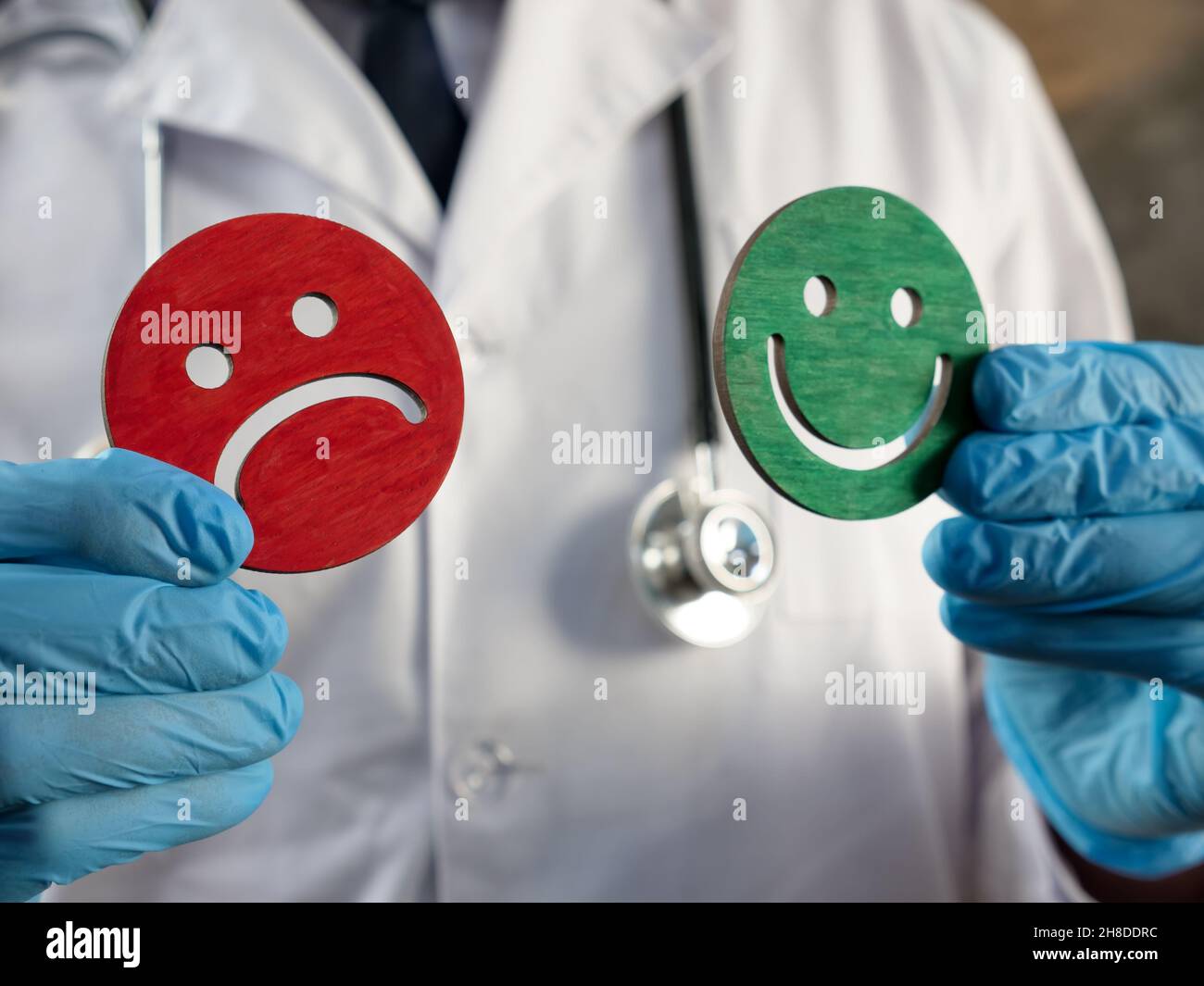 Umfrage zur Patientenzufriedenheit. Doktor hält freudige und traurige Emoticons. Stockfoto