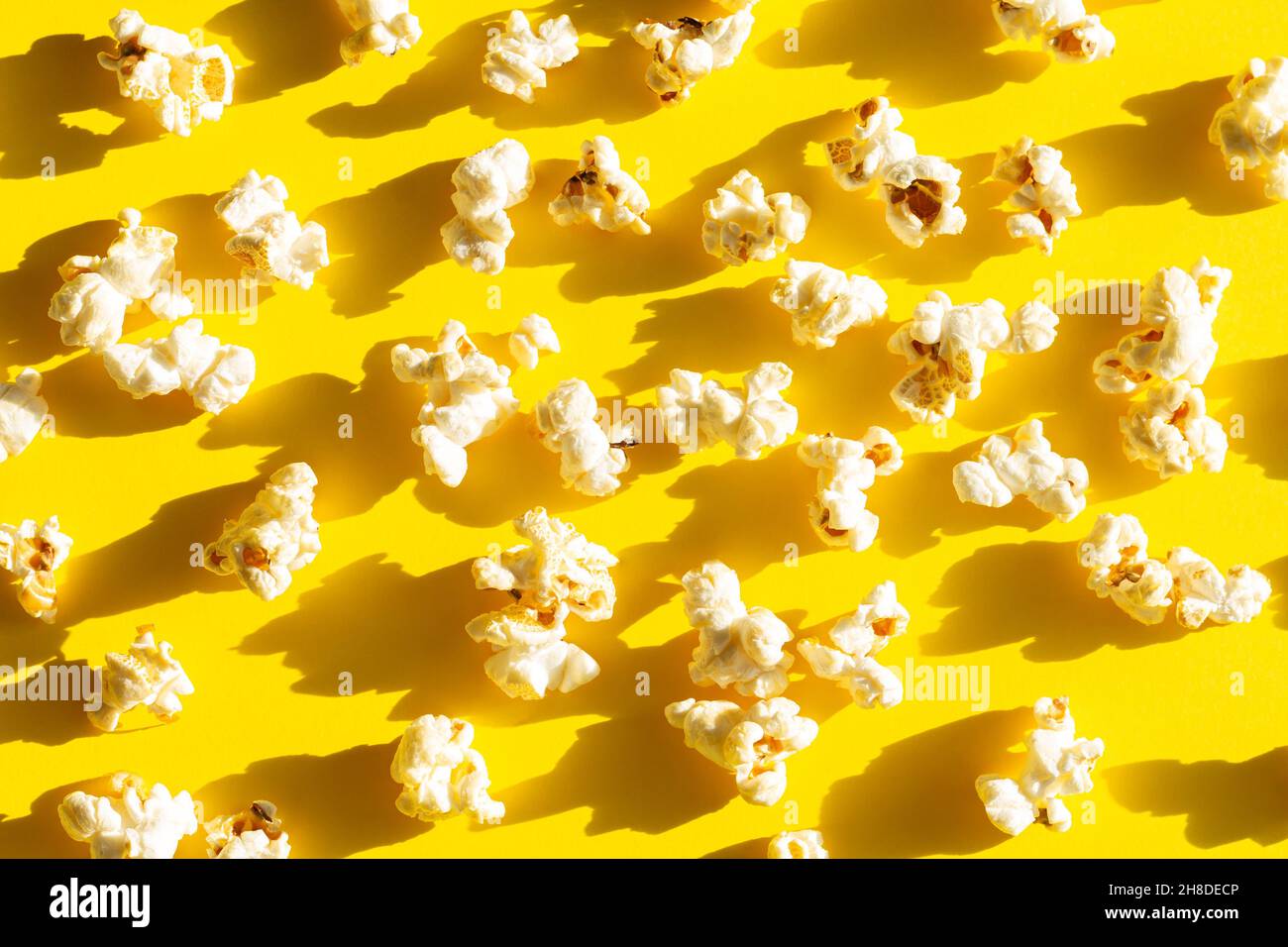 Knackiges, verstreutes Popcorn auf gelbem Hintergrund, Draufsicht. Das beste Essen für das Kino Stockfoto