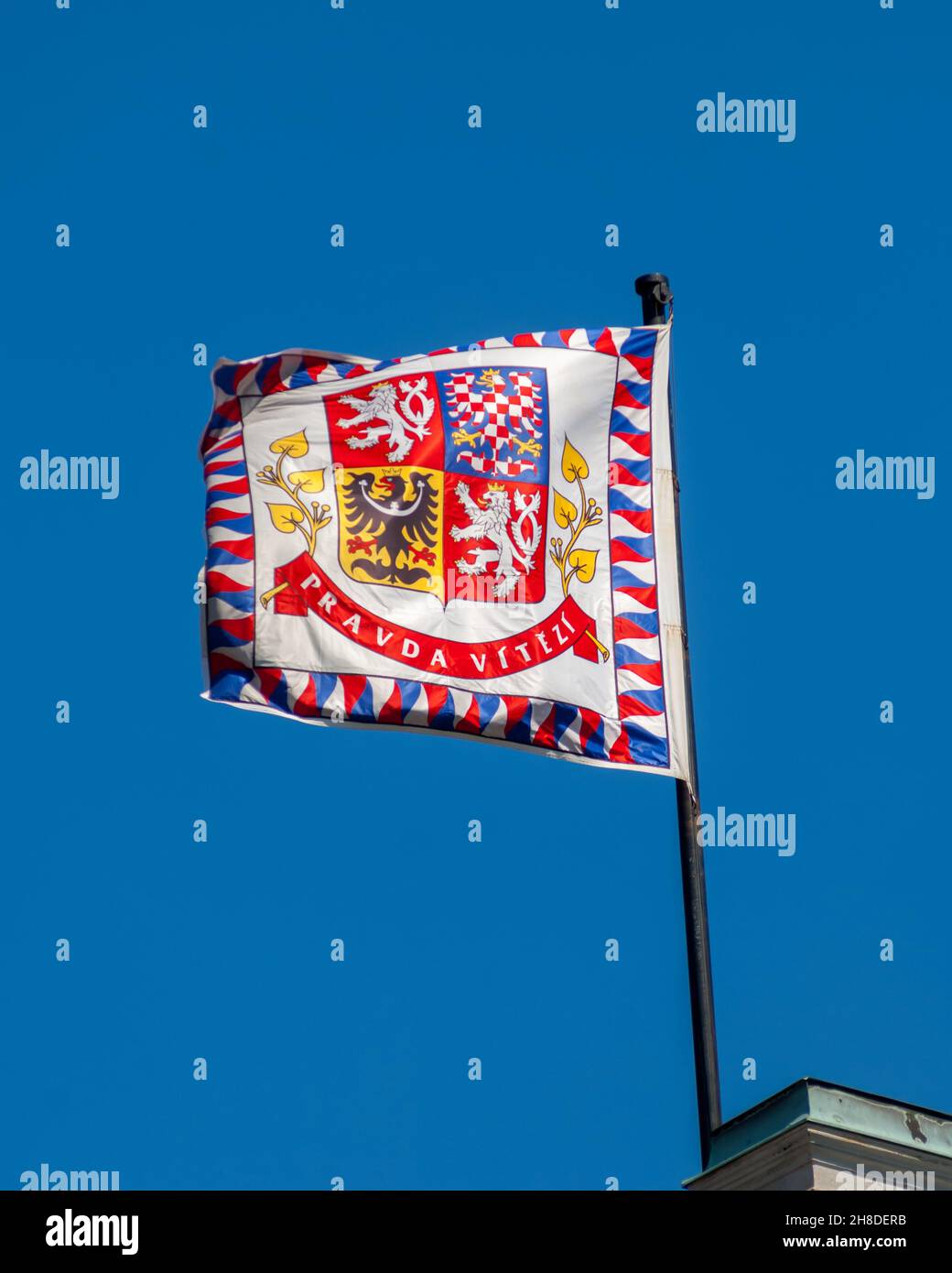 Das Presidential Standard und Wappen der Tschechischen Republik, das gegen einen tiefblauen Himmel über der Prager Burg fliegt Stockfoto