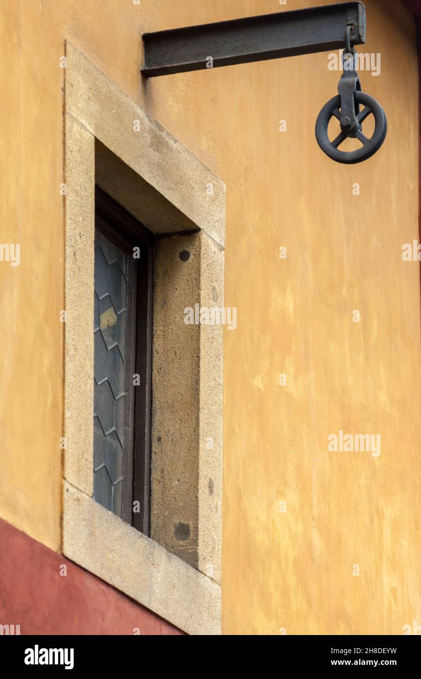 Ein an einem Eisenbalken aufgehängtes Rollenrad auf einem mittelalterlichen Gebäude am Ende der malerischen mittelalterlichen „Goldenen Gasse“ der Prager Burg Stockfoto