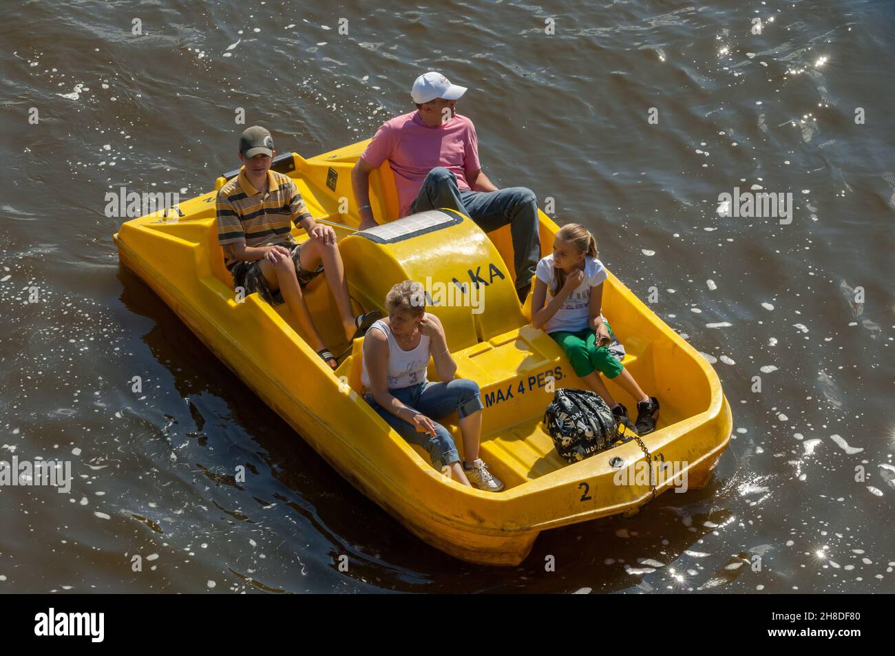 Eine Familie genießt einen sonnigen Tag auf der Moldau in einem leuchtend gelben Tretboot Stockfoto