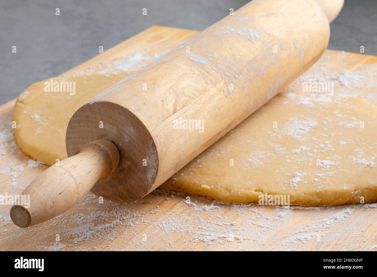 Frischen Teig zum Backen mit einem hölzernen Nudelholz und Mehl aus der Nähe vorbereiten Stockfoto