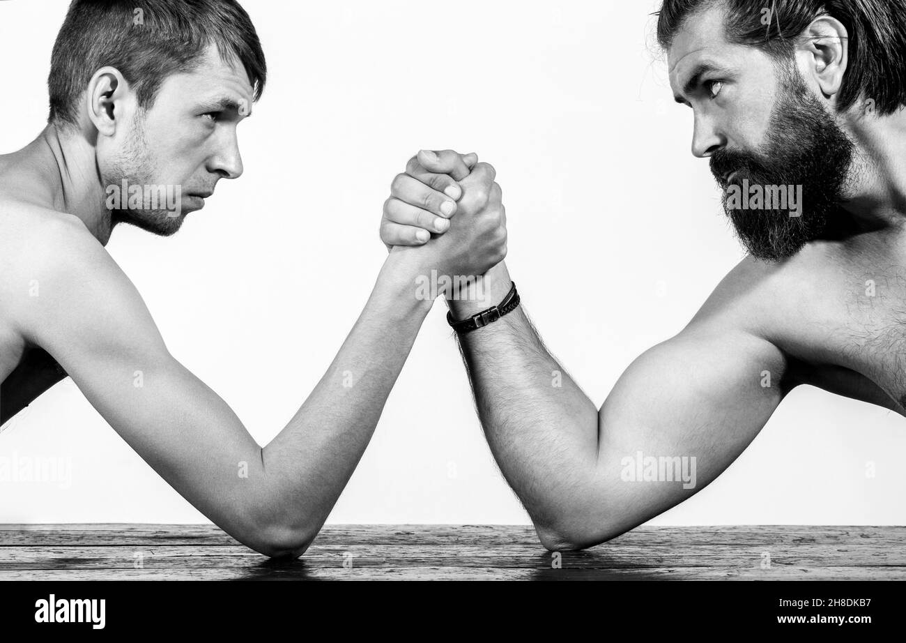 Zwei Männerhände umklammten Arm Wrestling, stark und schwach, ungleiche Übereinstimmung. Stark muskulös bärtigen Mann Arm Ringen ein mickrigen schwachen Mann. Arme ringen dünn Stockfoto
