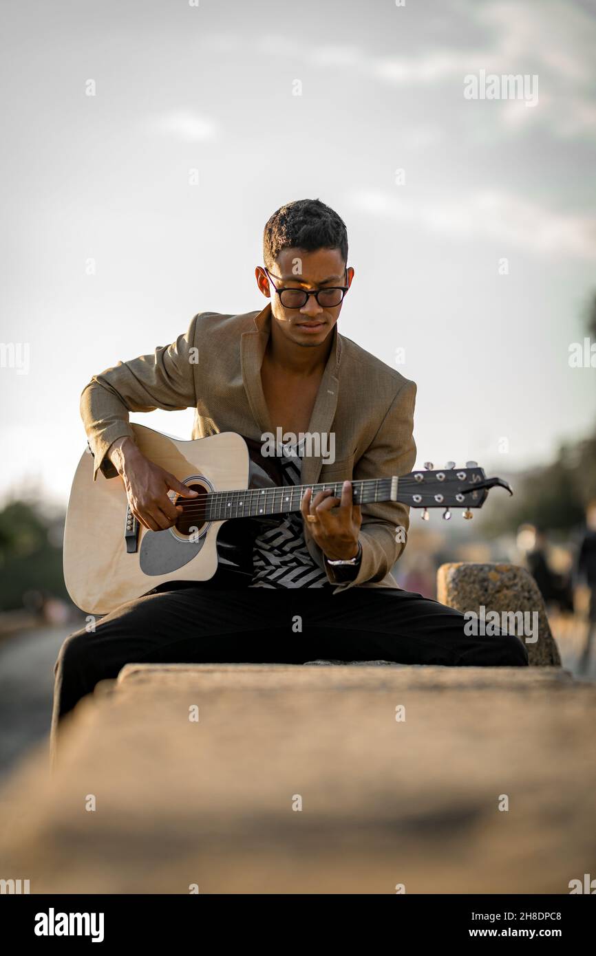 Porträt eines lateinischen Mannes, der während des Sonnenuntergangs auf der Straße Gitarre spielt Stockfoto