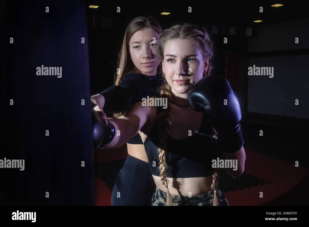 Frauen Fitness-Boxen Training im Fitnessstudio. Die Trainerin hilft der  Sportlerin, einen Schlag auf einen Boxsack richtig auszuführen  Stockfotografie - Alamy