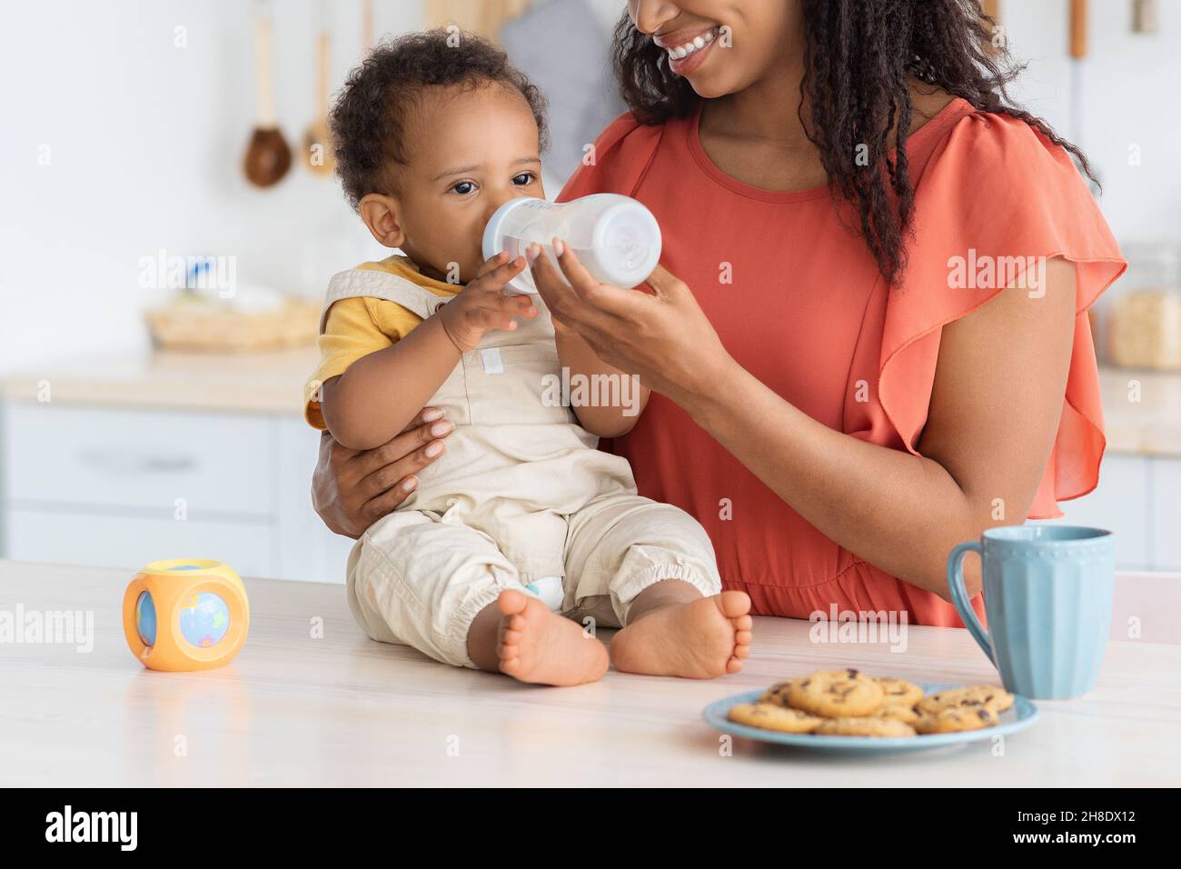 Durstig Entzückend Schwarzes Kleinkind Baby Trinkwasser Aus Flasche In Der Küche Stockfoto