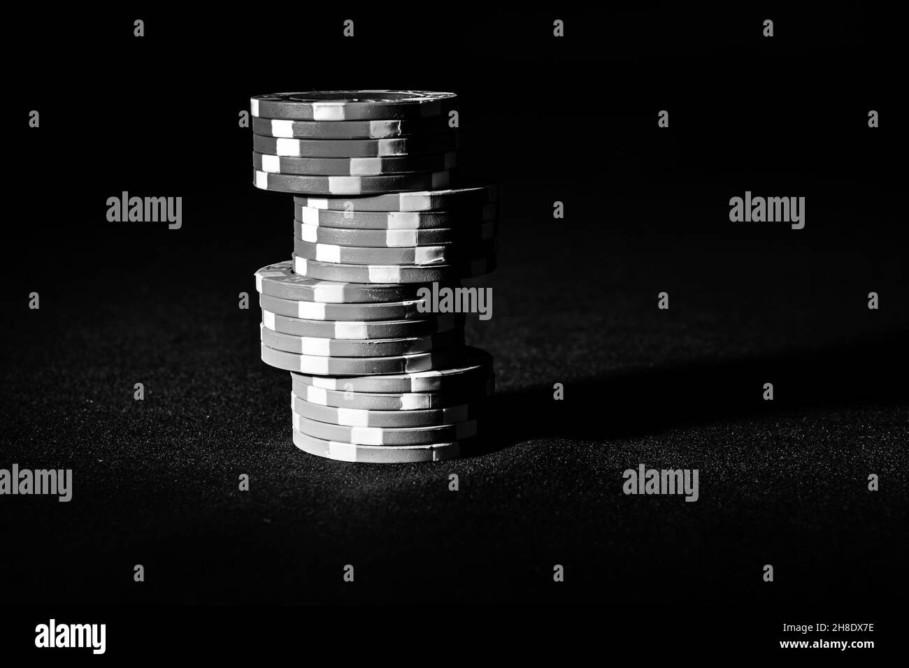 Graustufenaufnahme eines Stapels von Pokerchips, isoliert auf schwarzem Hintergrund mit einem Kopierraum Stockfoto