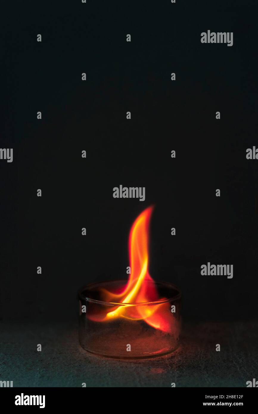 Rote Flam, die durch das Verbrennen von Lithiumchlorid in einer Glasschale entsteht. Stockfoto
