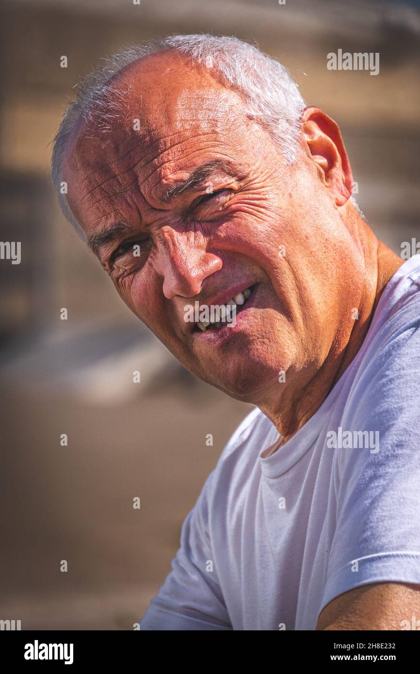 Vertikales Porträt eines hispanischen Mannes mittleren Alters, der vor dem Sonnenlicht runzelte Stockfoto
