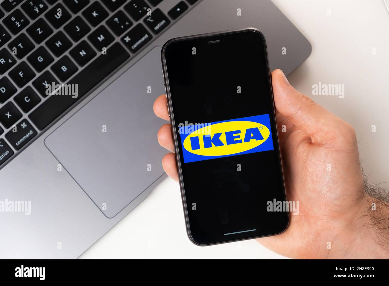 IKEA mobile Anwendung auf dem Smartphone-Bildschirm. Ein Mobiltelefon in einer Männerhand in der Nähe eines offenen Laptops. Weißer Hintergrund. November 2021, San Francisco, USA Stockfoto