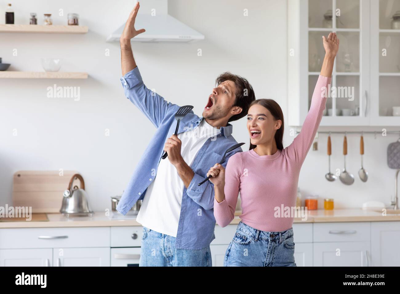 Glücklich emotional lustig Millennial europäischen Dame und Kerl haben Spaß zusammen, singen Lied an imaginären Mikrofon Stockfoto