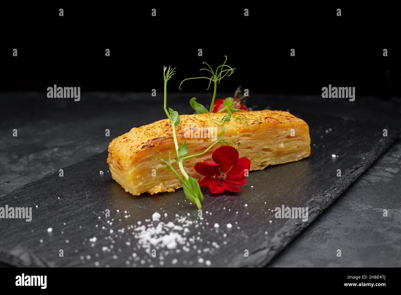 Dauphinua Kartoffelgratin mit Kirschtomaten auf schwarzem Stein Stockfoto