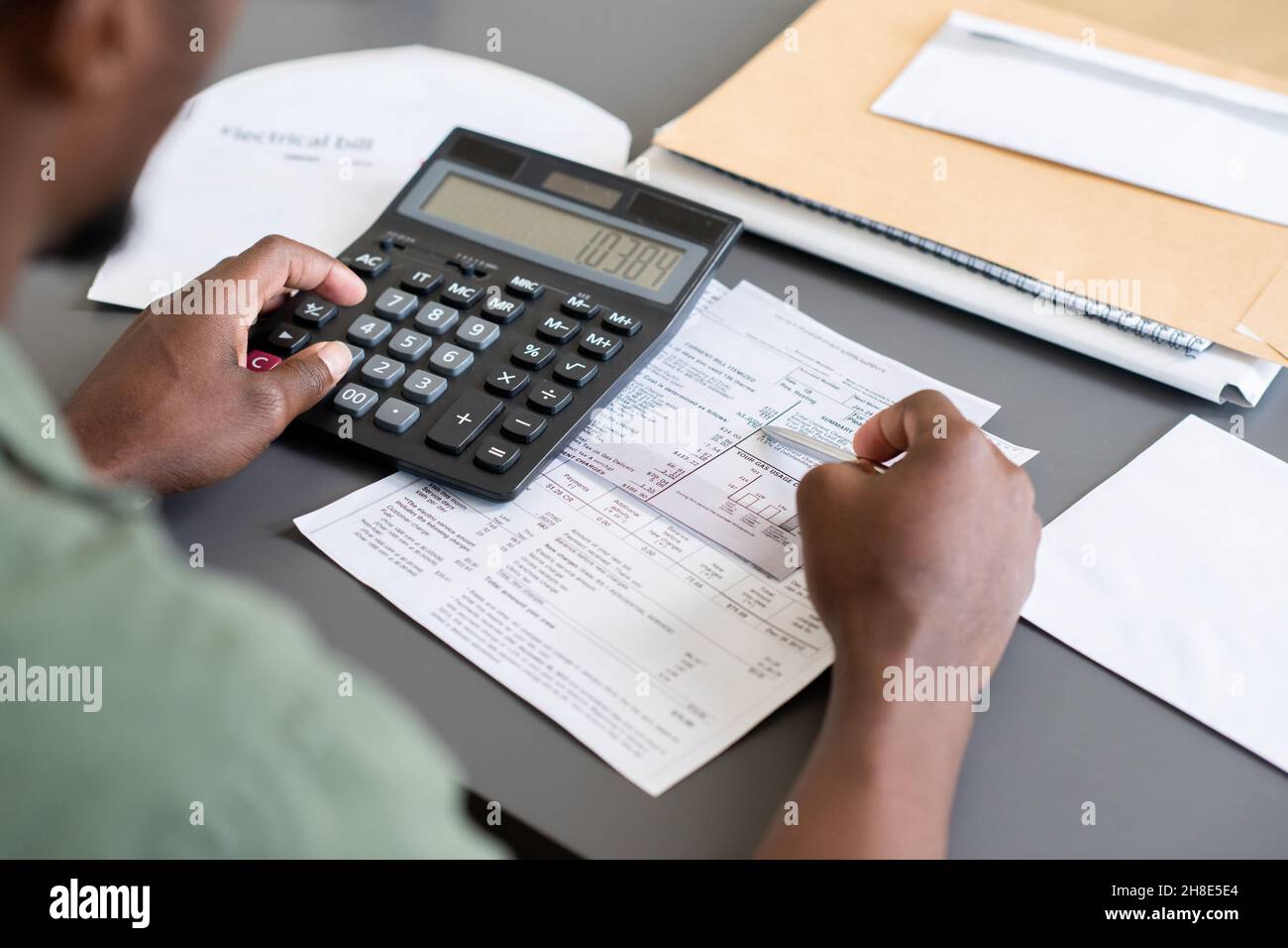 Nahaufnahme eines nicht erkennbaren blackmans, der am Tisch sitzt und Rechnungen überprüft, während er die persönlichen Finanzen berechnet Stockfoto