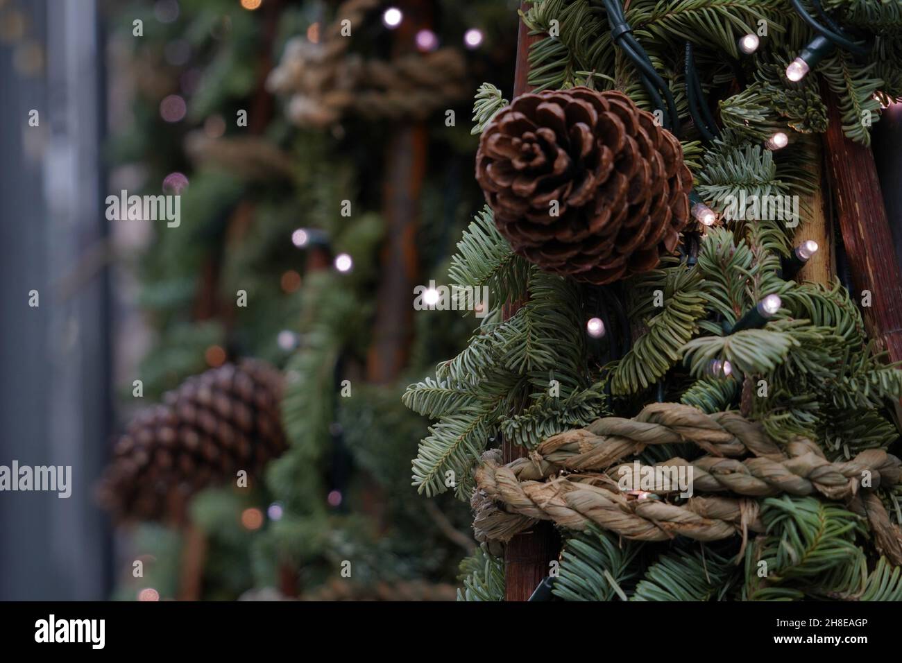 Weihnachtsdekoration aus Nadelbäumen mit Zinnen und winzigen Lichtern, die an den Zweigen befestigt sind. Saisonales Thema mit Fokus auf den Vordergrund. Stockfoto