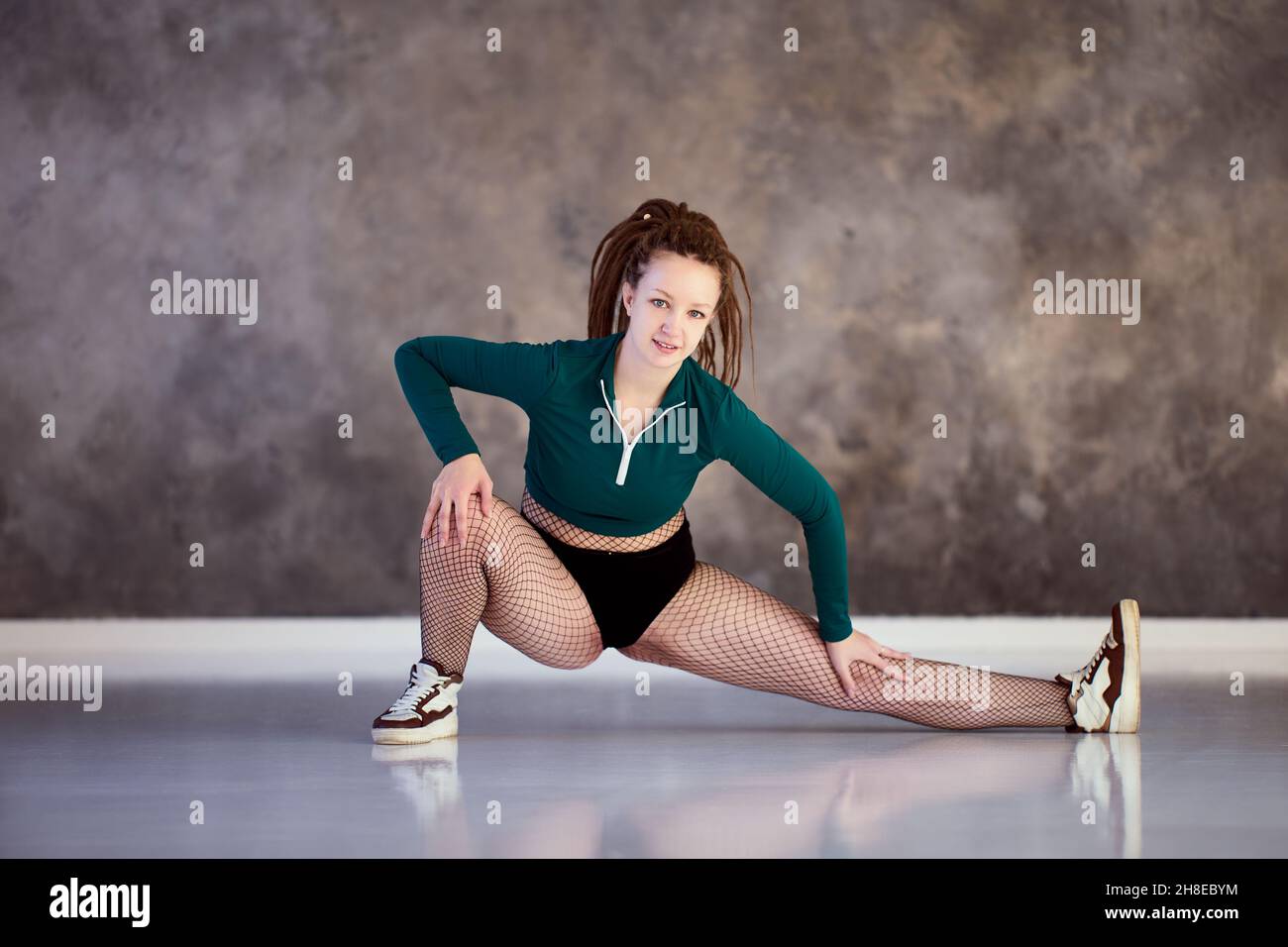 Weibliche Twerk-Tänzerin streckt sich im Tanzstudio. Stockfoto