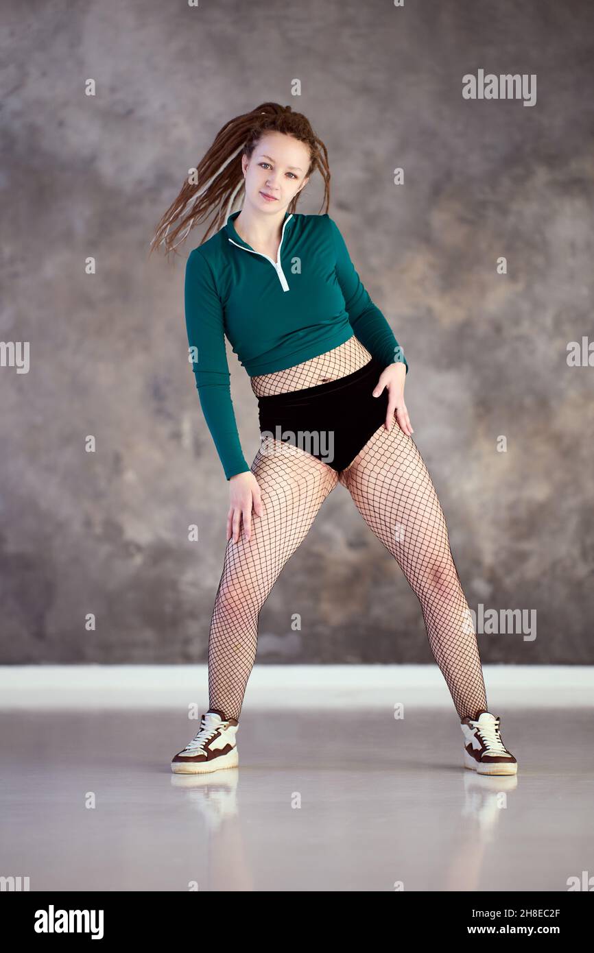 Tänzerin trainiert im twerk Tanzstudio, Frau im langärmligen Oberteil und Netzstrumpfhose tanzt im Fitnessstudio. Stockfoto
