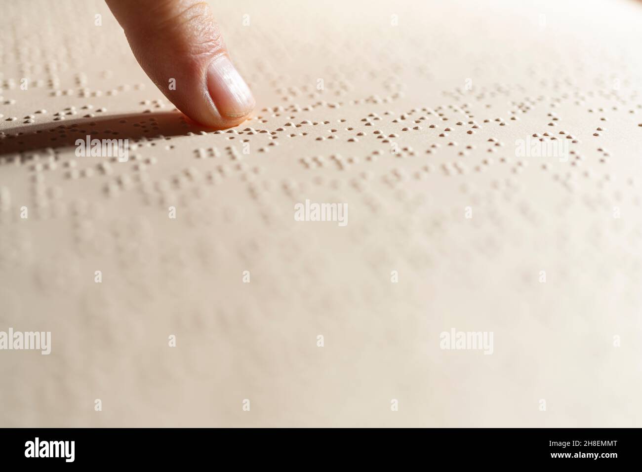 Ein Finger, der dem Lesen einer im Braille-Alphabet geschriebenen Seite folgt, dem taktilen Lesesystem zur Erleichterung für Blinde Stockfoto