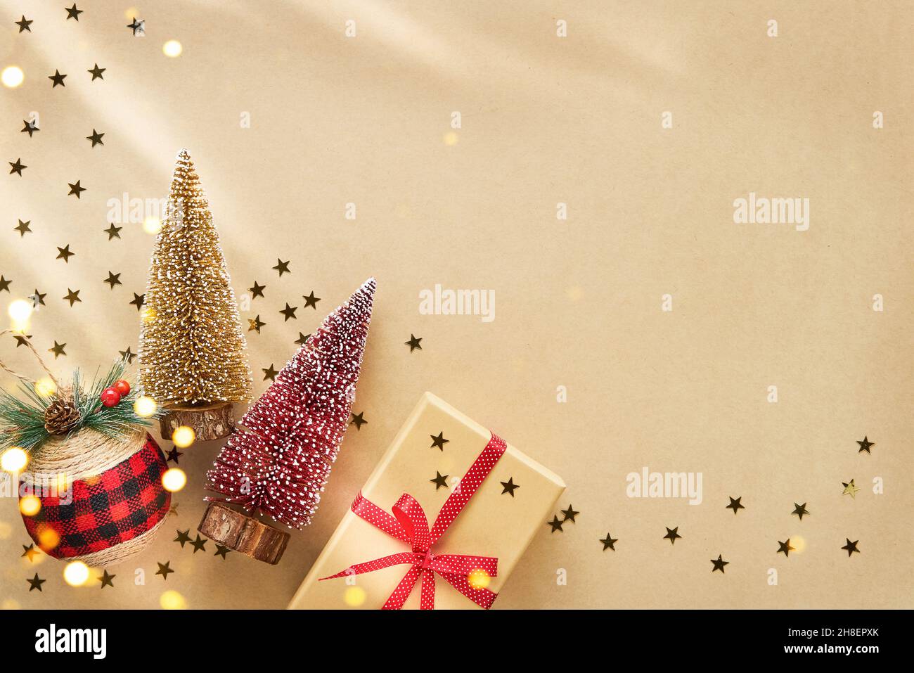 Weihnachtsdekoration und Geschenkbox mit rotem Band auf einem Kraftpapier-Hintergrund. Flach liegend, Platz für Text kopieren Stockfoto