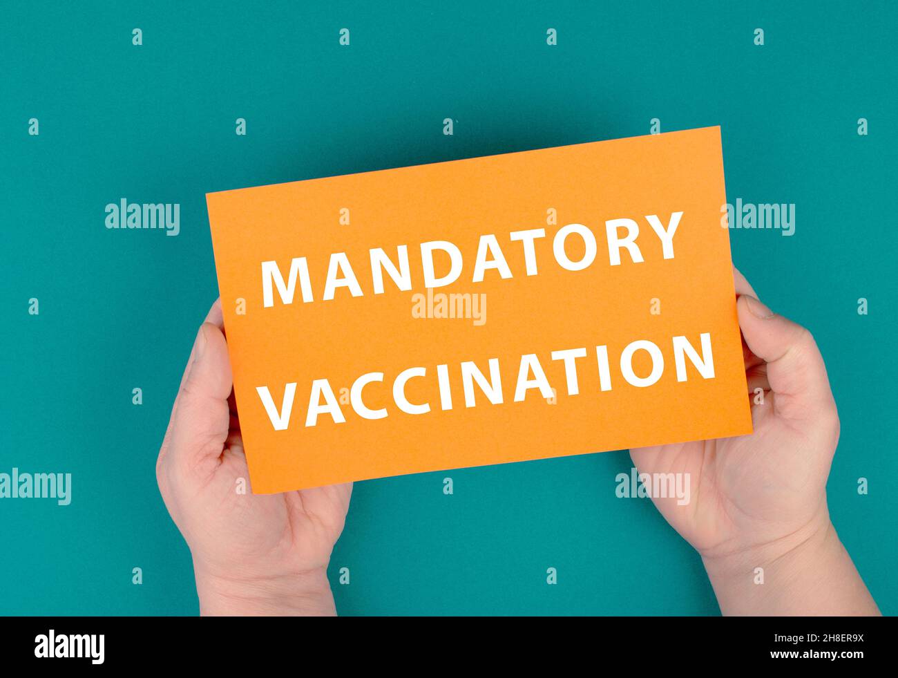 Das Wort obligatorische Impfung steht auf dem Papier, Zwangsimpfstoff, Covid-19-Vorschriften, Orange und Benzinfarbe Stockfoto