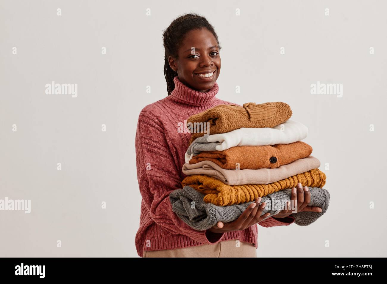 Porträt einer jungen afroamerikanischen Frau mit einem Stapel handgestrickter Pullover und einem Lächeln auf die Kamera Stockfoto