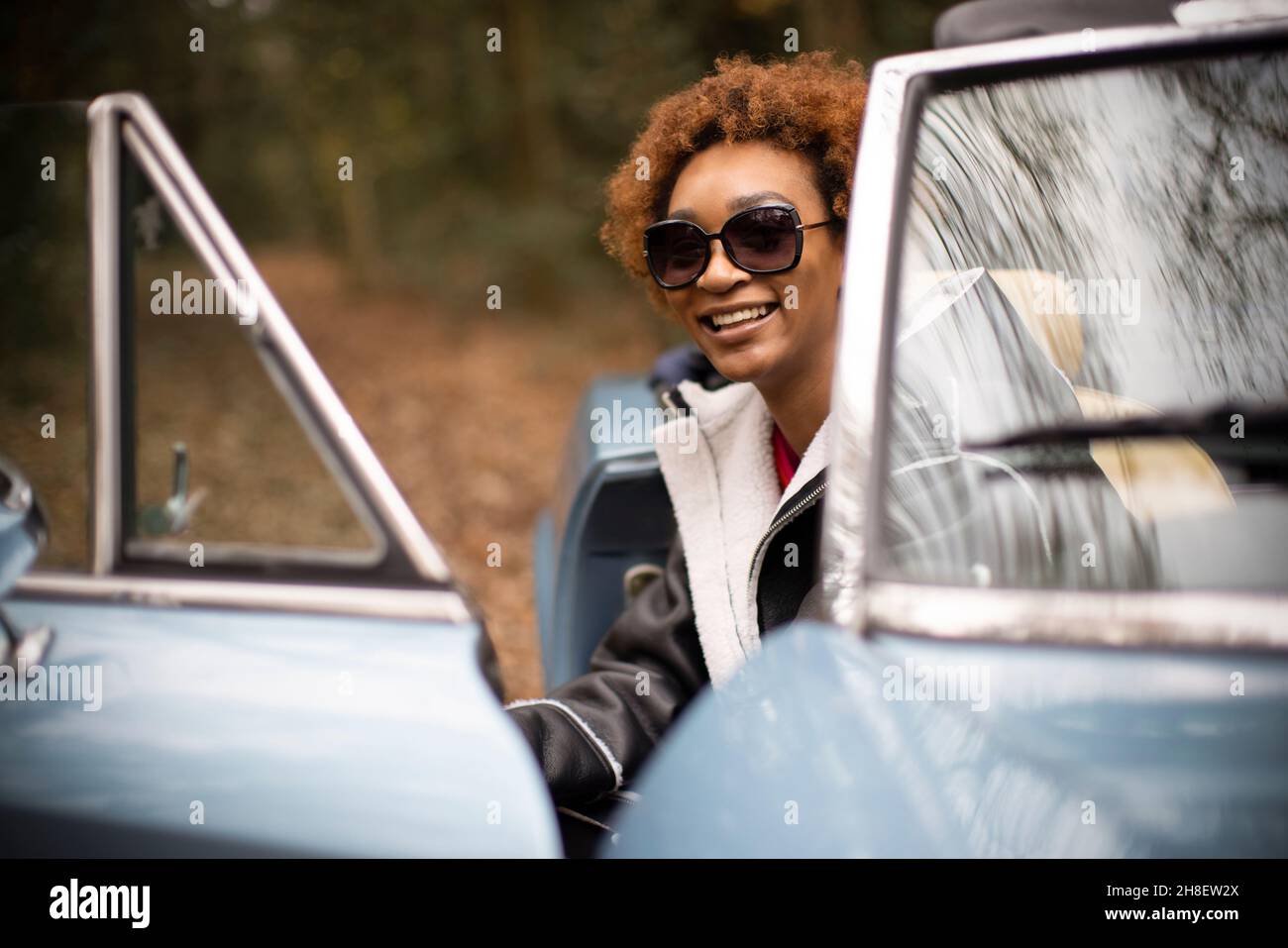 Porträt glücklich unbeschwerte junge Frau, die aus dem Cabrio herauskommt Stockfoto