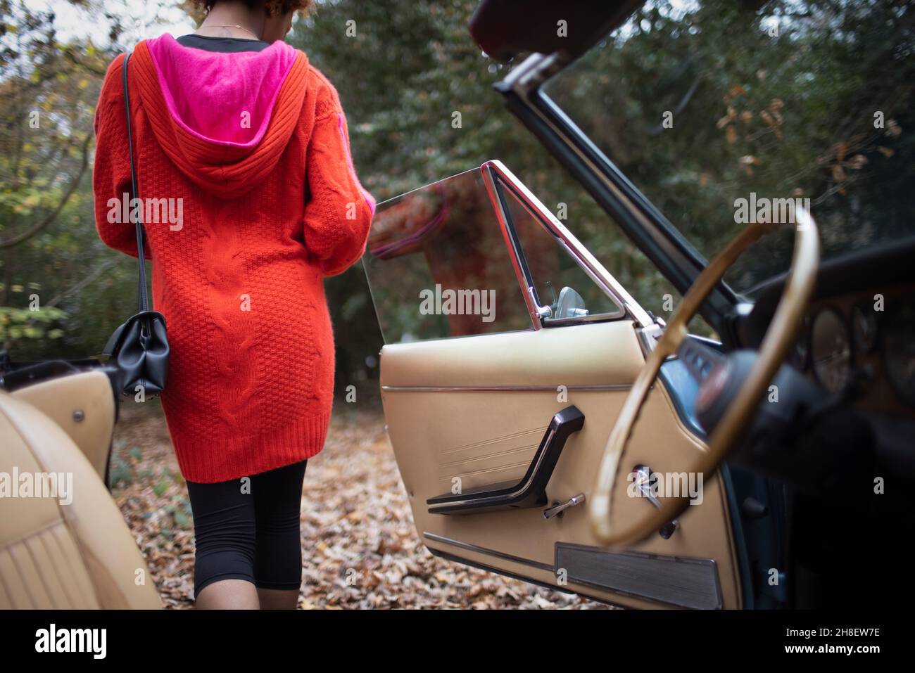 Junge Frau, die im Herbstpark aus dem Cabrio aussteigen wird Stockfoto