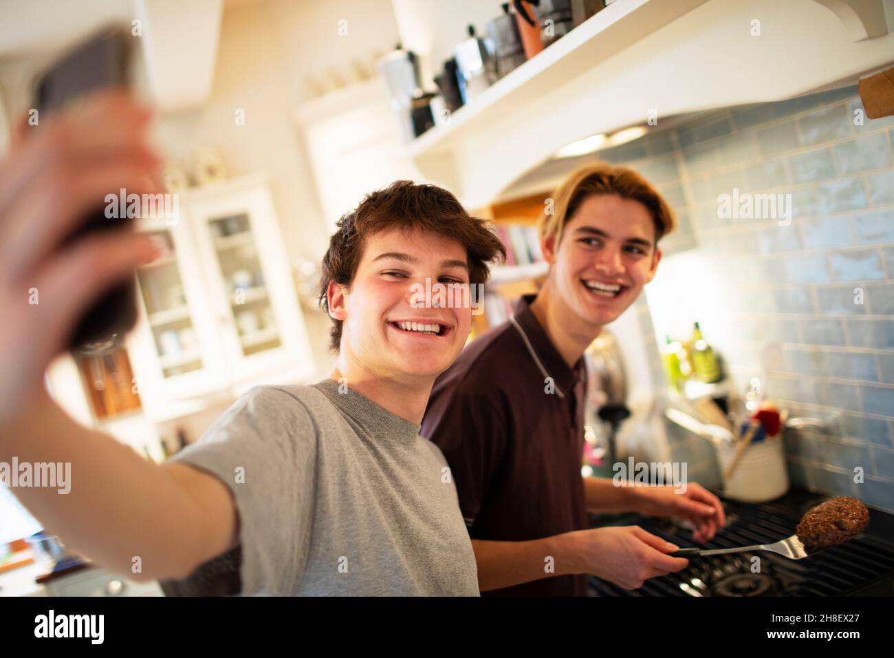 Glückliche Teenager, die Selfie machen und in der Küche kochen Stockfoto