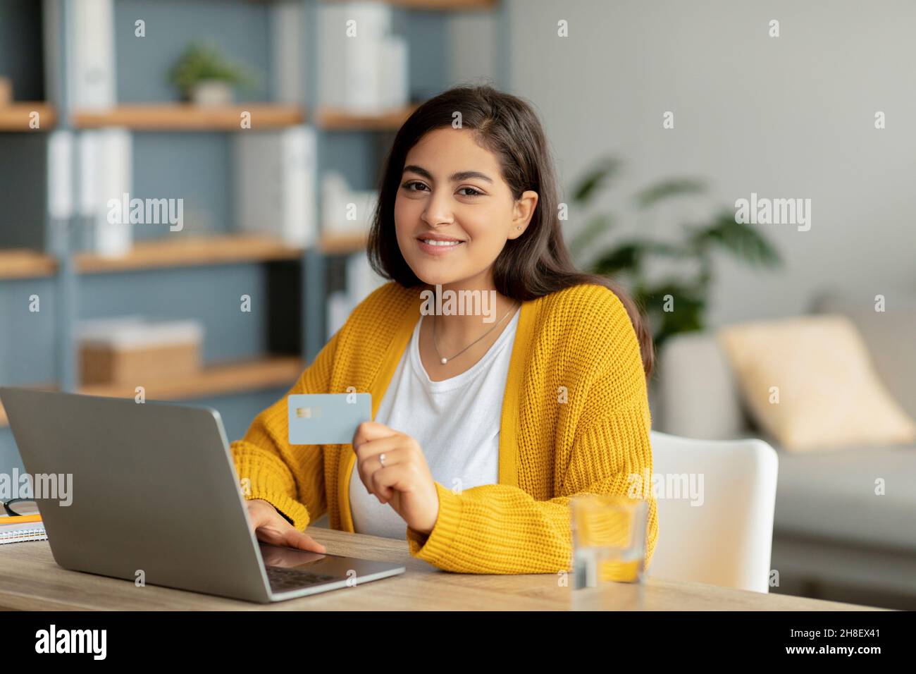 Online-Wallet und Banking-Konzept. Glückliche arabische Frau mit Laptop und Kreditkarte, die finanzielle Transaktion Stockfoto