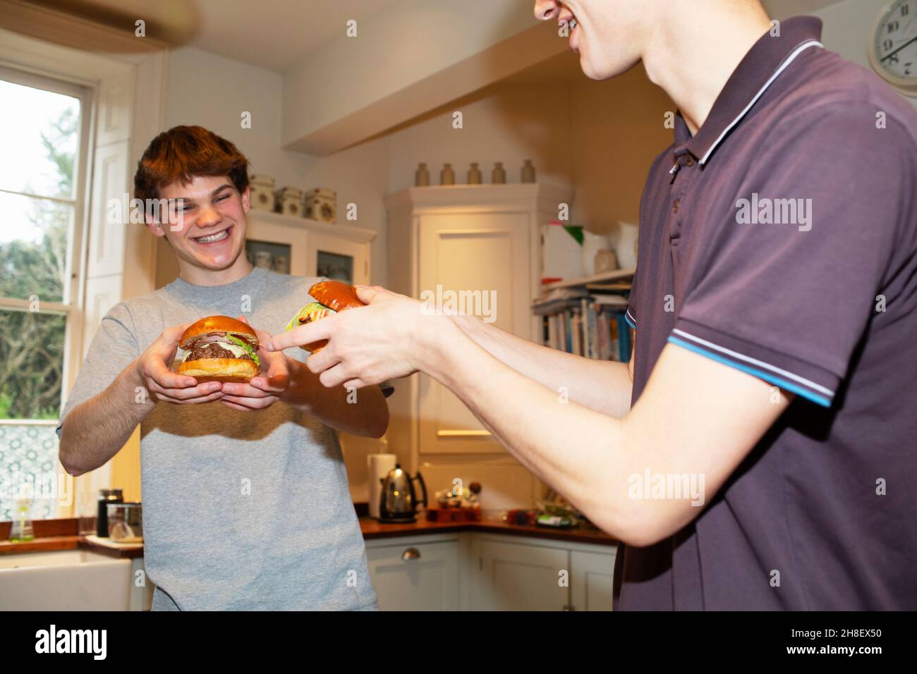 Glückliche Teenager, die zu Hause Hamburger essen Stockfoto