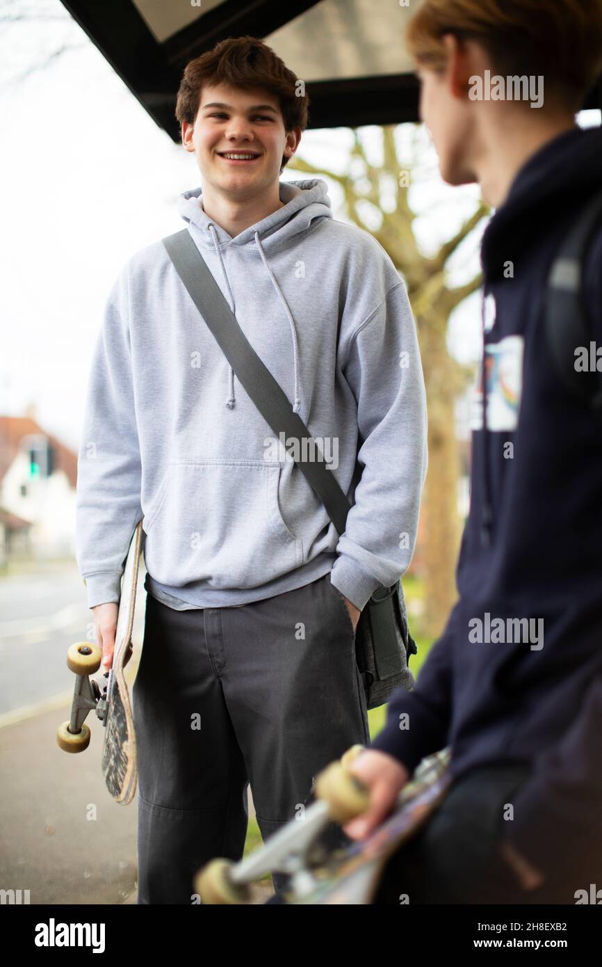 Teenager-Jungs mit Skateboards warten an der Bushaltestelle Stockfoto