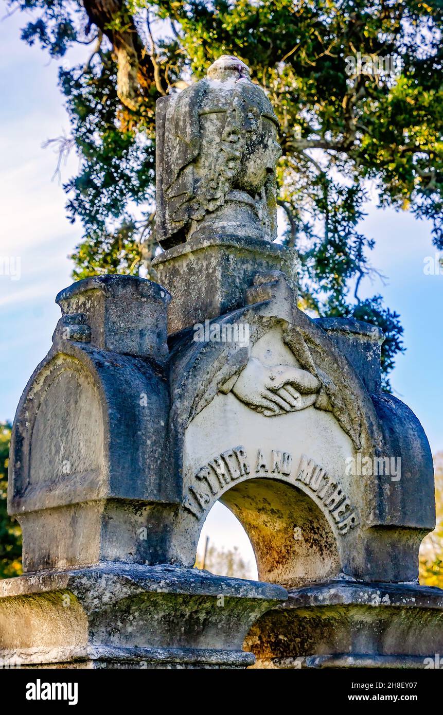 Auf dem Magnolia Cemetery in Mobile, Alabama, befindet sich ein reich verzierter Grabstein mit häufigen Grabkunstsymbolen, darunter verschlossene Hände und eine drapierte Urne. Stockfoto