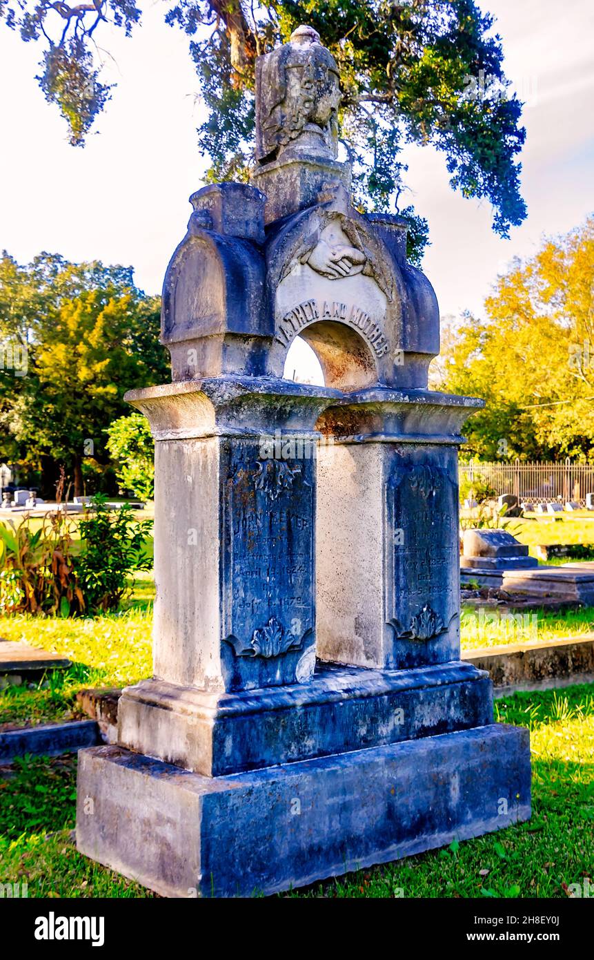 Auf dem Magnolia Cemetery in Mobile, Alabama, befindet sich ein reich verzierter Grabstein mit häufigen Grabkunstsymbolen, darunter verschlossene Hände und eine drapierte Urne. Stockfoto