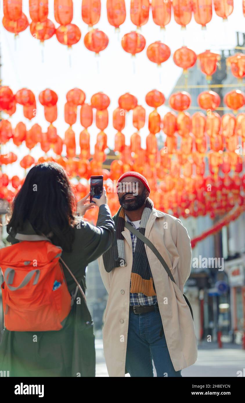 Frau mit Kameratelefon fotografiert Ehemann in Chinatown, London, Großbritannien Stockfoto