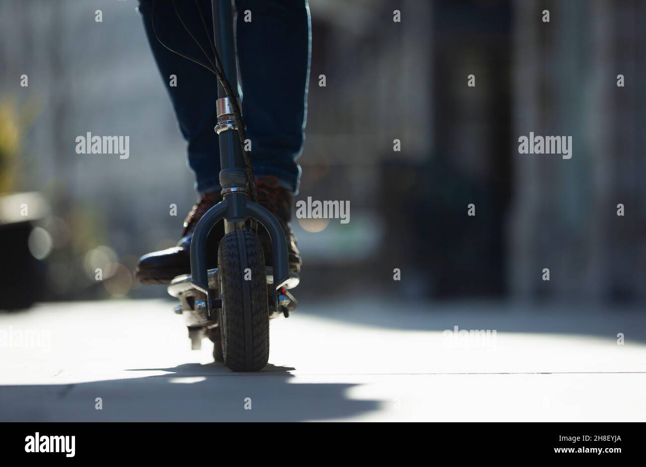 Nahaufnahme Mann Reiten Elektro-Roller auf sonnigen Bürgersteig Stockfoto