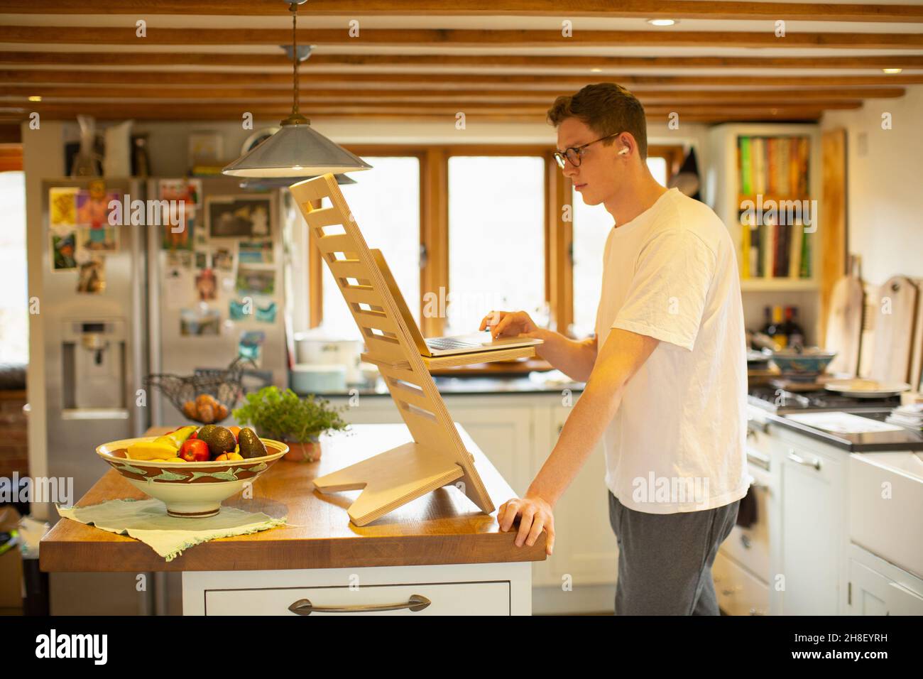 Mann, der am Laptop arbeitet und in der Küche auf dem Schreibtisch steht Stockfoto