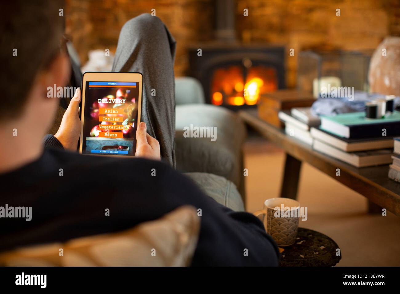 Mann, der im Wohnzimmer das Menü zum Mitnehmen auf einem digitalen Tablet anschaut Stockfoto