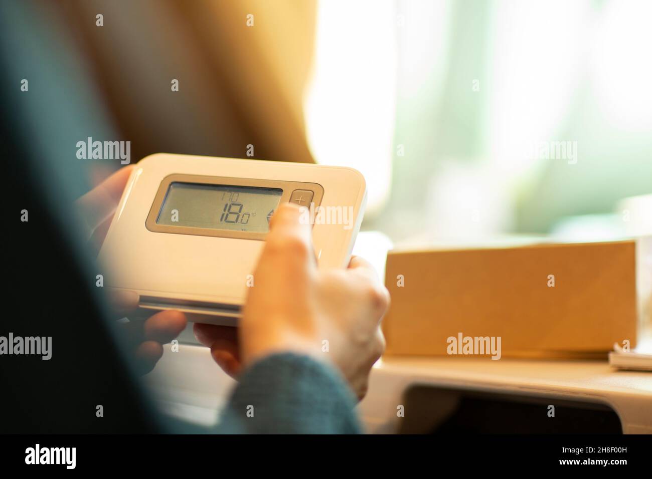 Frau, die den Thermostat zu Hause anpasst Stockfoto